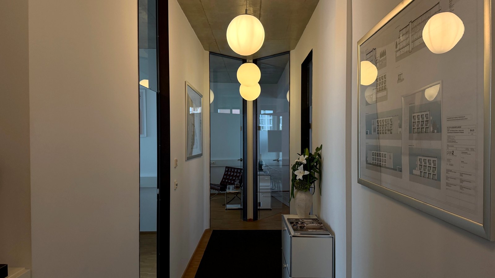 Flur im Büro der BM Property Partners, an der Wand gerahmte Baupläne laufender Projekte